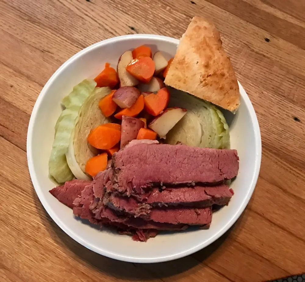 A plate of sliced beef with cabbage, carrots and potatoes