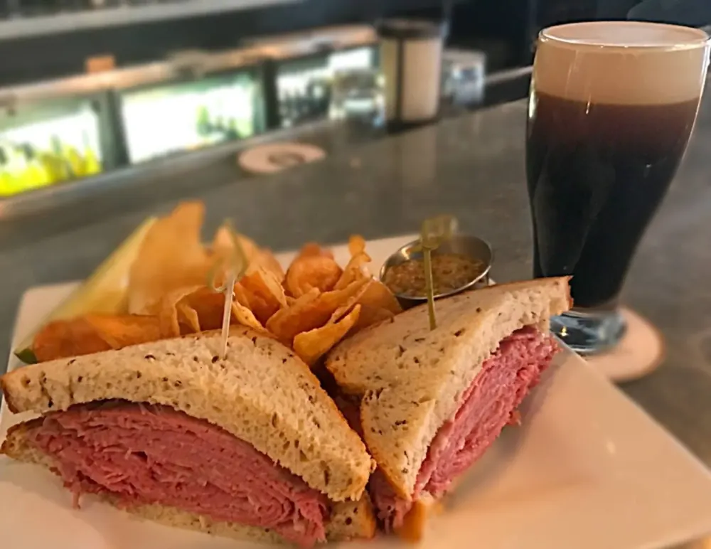 A sandwich on rye with chips and a stout