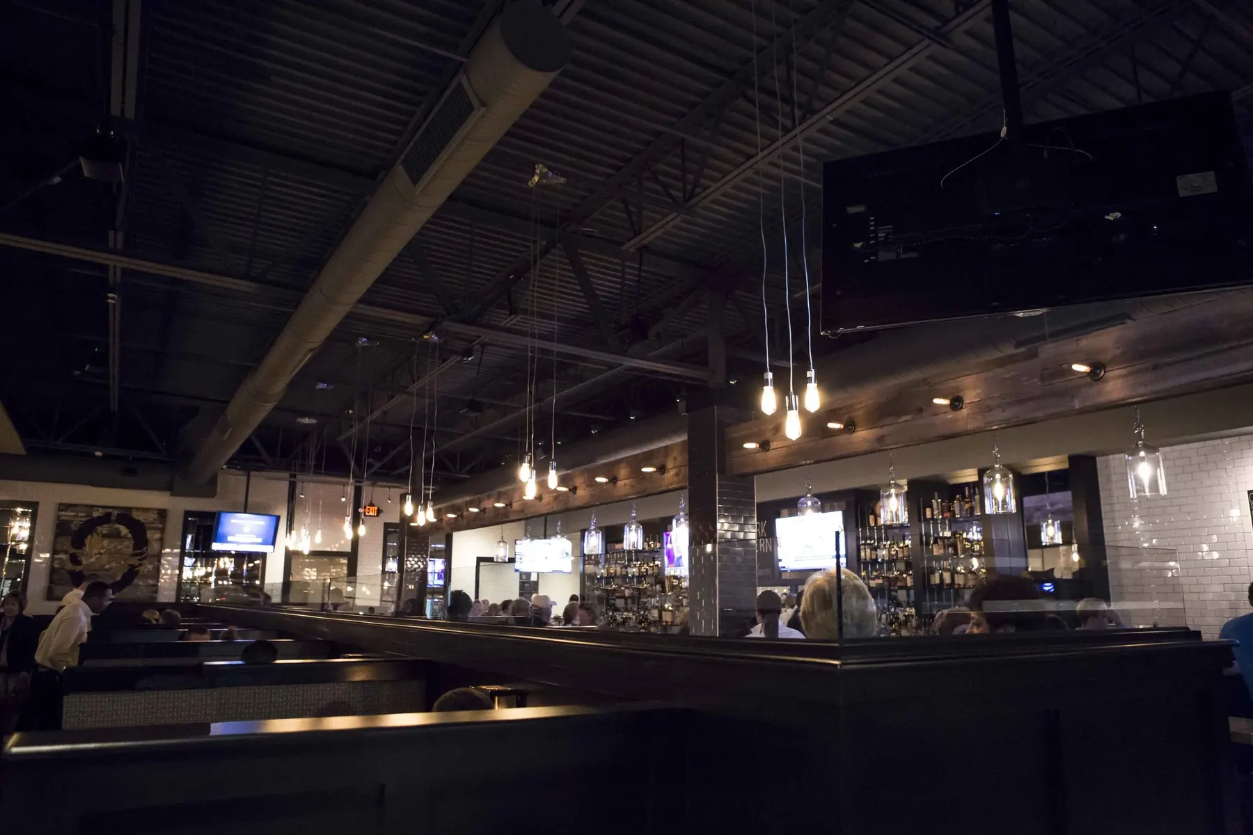 The back bar at night, shelves of bottles under Edison bulbs